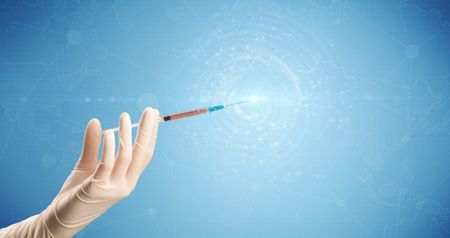 Female doctor hand holding syringe with blue background and shine