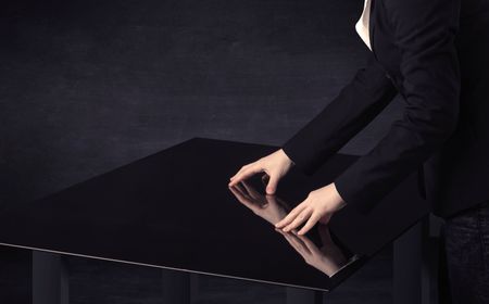 Close up of a hand touching smart table with copy space on black background