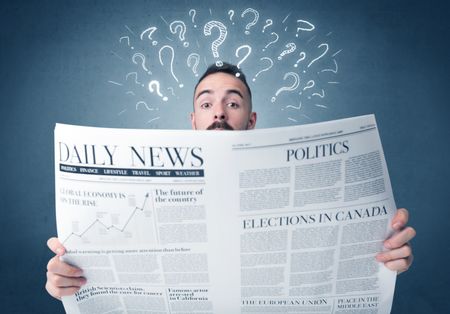 Young confused businessman reading daily newspaper with question marks above his head