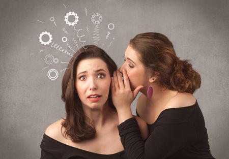 Two girlfriends in elegant black dress sharing secrets with each other concept with drawn rack cog wheels and spiral lines on the wall background.