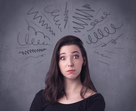 A cute female student making funny face expressions with pressure and problems in her head illustrated by drawn lines, marks and spirals on the urban wall background concept.