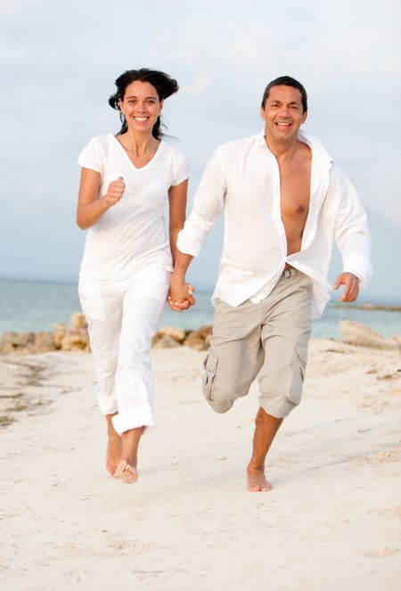 Beautiful happy couple running at the beach