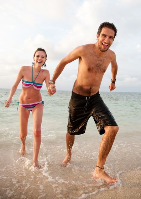 Happy young couple running at the beach