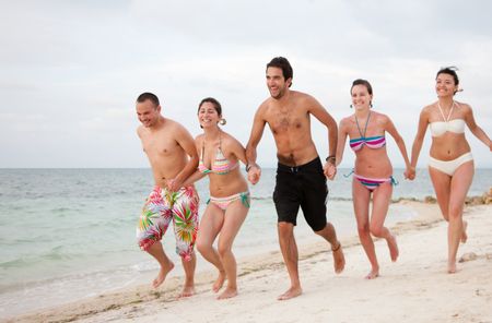 Happy group of friends running at the beach