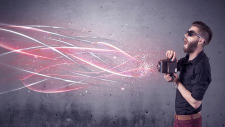 A stylish funny hipster person holding a vintage camera and taking photographs illustrated with glowing red, white lines concept