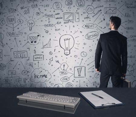 An intelligent office worker drawing strategy ideas and future plan keywords on wall at a brainstorming meeting in office concept