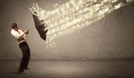 Business man holding umbrella against dollar rain concept on grungy background