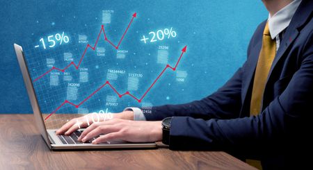 An elegant businessman working on graph statistics calculation using a laptop with clear blue background concept