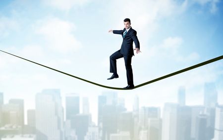 City scape, tall buildings and clouds on clear blue sky with business person balancing on black rope concept