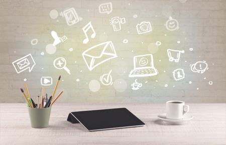 Social media online communication concept with icons and close up of business office desk full of work equipement