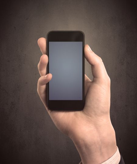 Caucasian hand in business suit holding a blank screen smartphone
