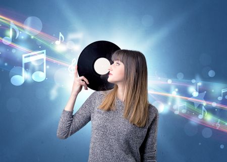 Young lady holding vinyl record on a blue background with musical notes behind her