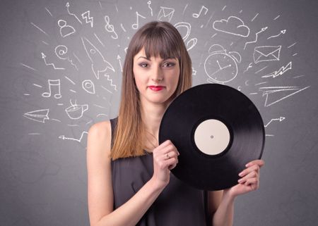 Young lady holding vinyl record on a grey background with mixed scribbles behind her