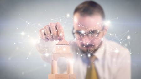 Young handsome businessman using wooden building blocks with interconnected lines and dots around him