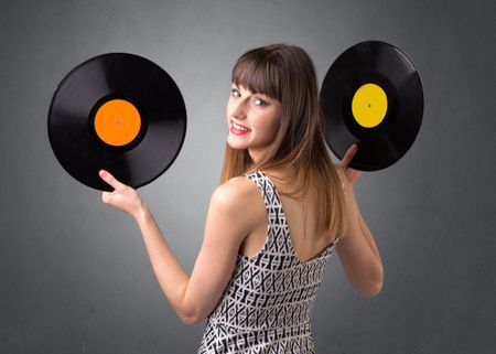 Young lady holding vinyl record on a grey background