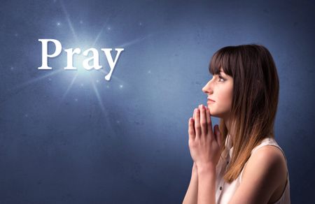 Young woman praying on a blue background with the word Pray written above her