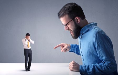 Young professional businessman being angry with an other miniature businessman 