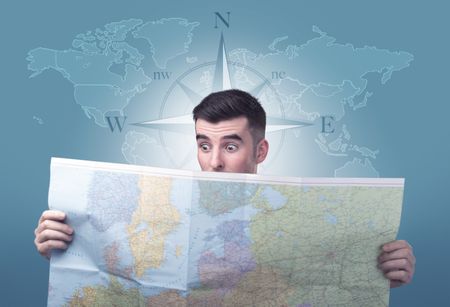 Handsome young man holding a map with a world map and a compass behind him