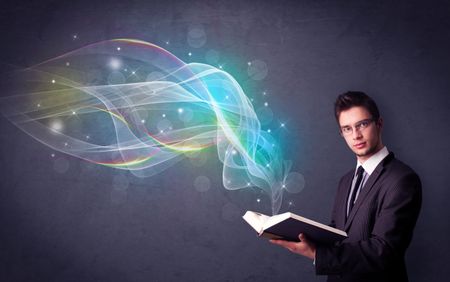 Casual young man holding book with rainbow waves flying out of it