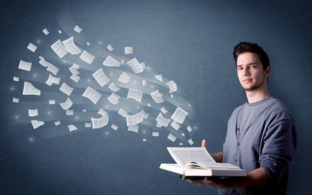 Casual young man holding book with pages flying out of it