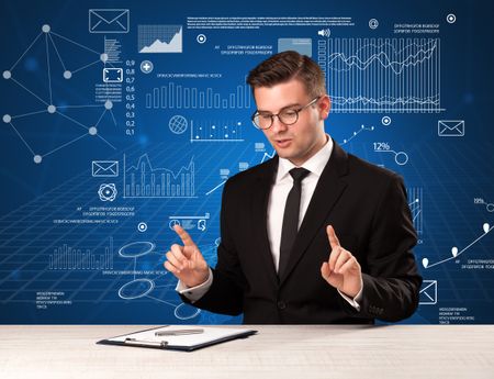 Young handsome businessman sitting at a desk with blue charts and data behind him