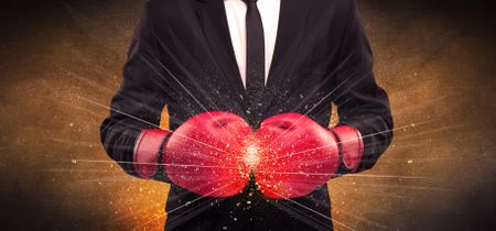 A successful powerful business person in red boxing gloves concept with illustrated power lines and pieces falling apart in front of explosion.