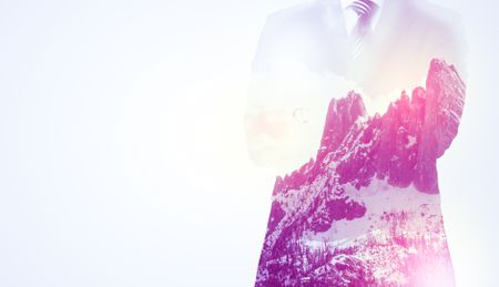  Young businessman in suit standing with sunny snowy mountain and trees graphic.