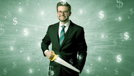 Handsome businessman holding tool with dollar symbols around and with green background