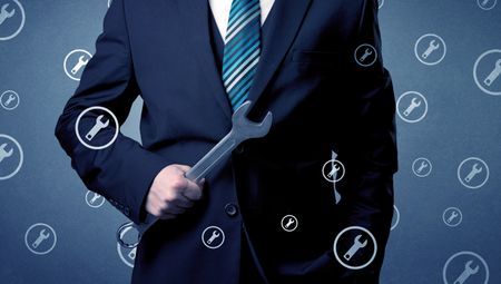 Young serious businesman holding tool with wrench icons around 