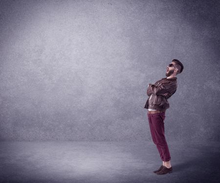 A hipster guy in stylish clothes shouting in front of an empty urban concrete wall background concept