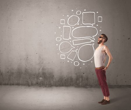 A comic hipster guy shouting in front of grey urban concrete wall with drawn empty text bubbles around his mouth concept