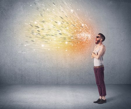 A young hipster guy with beard and sunglasses shouting in front of urban wall with vomit like colorful paint splatter on wall concept