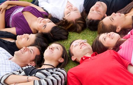 group of happy friends smiling and relaxing outdoors with heads together on the floor