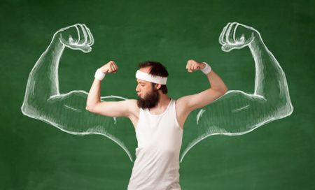 A young male with beard and glasses posing in front of green background, imagining how he would look like with big muscles, illustrated by white drawing concept.