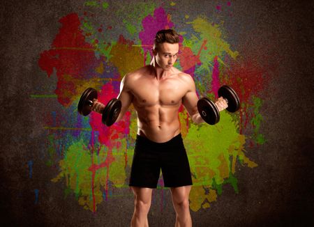 A muscular young bodybuilder lifting weight and showing his hot body with muscles in front of an urban painted wall concept