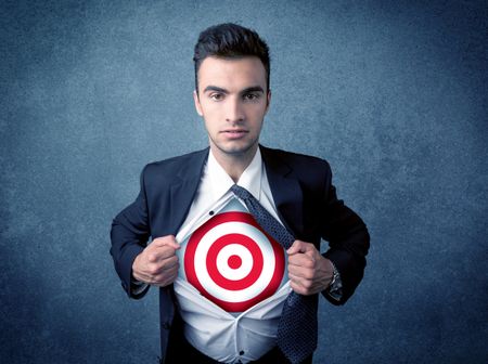 Businessman tearing his shirt off with target sign symbol on his chest concept on background