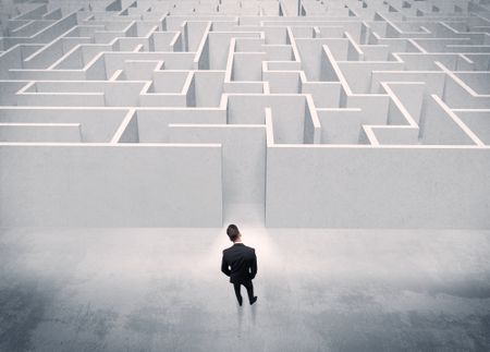 A good looking businessman with briefcase standing in front of white labirynth entrance about to make a decision concept