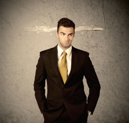 An elegant handsome business guy standing in front of wall with a bullet going through his head, making facial expressions concept