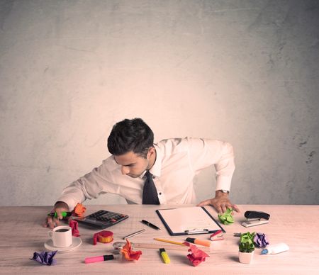 A young office worker sitting at desk working with keyboard, papers, highliter in front of empty clear background wall concept