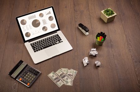 Pie chart graph icons and symbols on laptop screen with office accessories