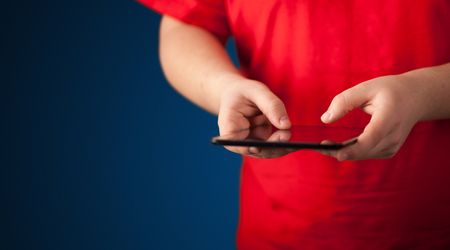 Close up of hand holding digital touchpad tablet device on background