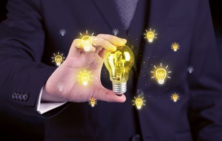 A creative businessman has a bright idea concept with office worker holding light bulb in foreground.