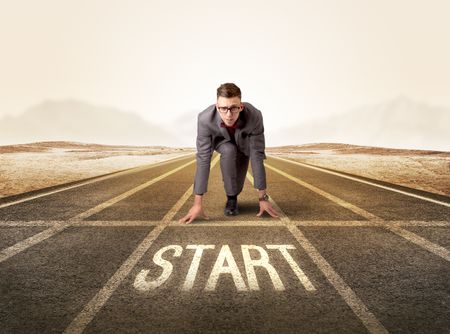 Young determined businessman kneeling before start line