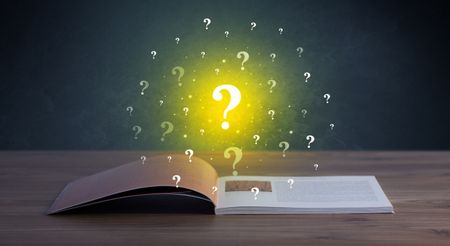 Yellow question marks hovering over open book 