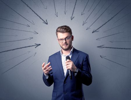 Businessman speaking into microphone with arrows pointing towards his head