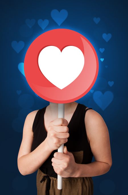 Casual young woman holding round sign with heart