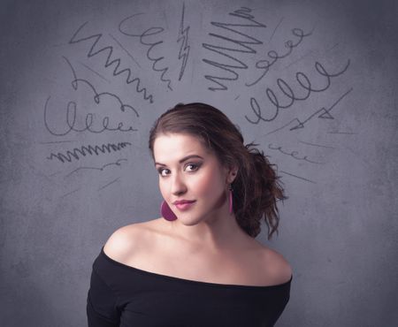 A cute female student making funny face expressions with pressure and problems in her head illustrated by drawn lines, marks and spirals on the urban wall background concept.