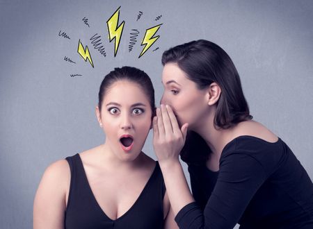 A beautiful girl in black dress sharing secrets to her girlfriend concept with drawn energetic electric yellow signs above her head on the wall background.