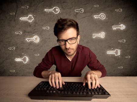 A young internet geek working online, hacking login passwords of social media users concept with glowing drawn keys on the wall