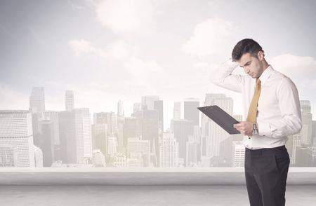 A young adult businessman standing in front of city landscape with skyscraper buildings and clouds concept